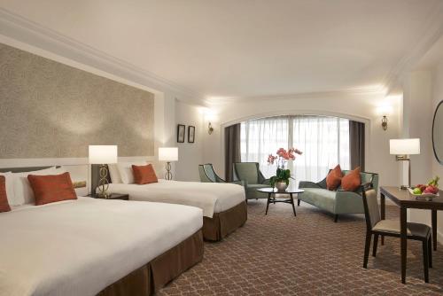 新加坡Orchard Rendezvous Hotel by Far East Hospitality的酒店客房带两张床和一张桌子以及椅子。