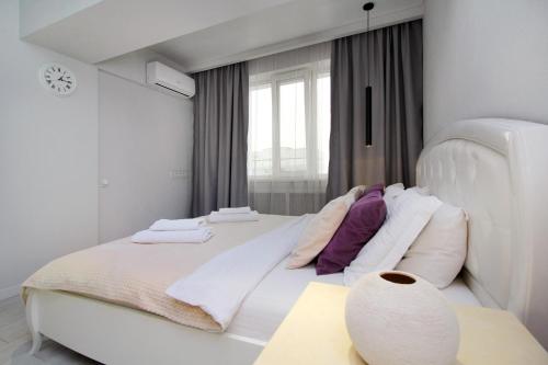 阿拉木图уютная квартира-студия в центре Алматы的白色卧室配有一张带枕头的大白色床