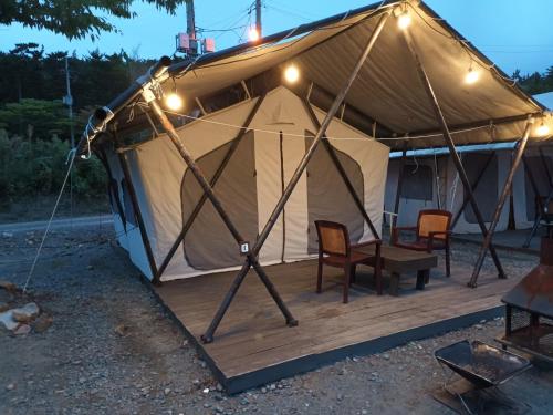 泰安Club Lespia in Taean的木制甲板上配有椅子和灯的帐篷