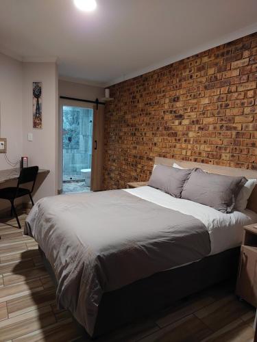 范德拜尔帕克Twins Guest House Astoni的一间带砖墙和大床的卧室
