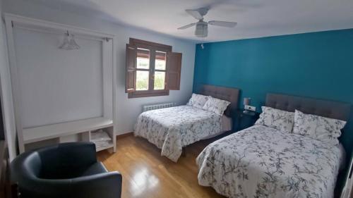 普里埃格·德·科尔多巴Paredejas del Rey的一间卧室设有两张床、一把椅子和一个窗户。