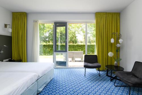 奈凯尔克小红屋酒店的一间卧室配有一张床、两把椅子和一个窗户