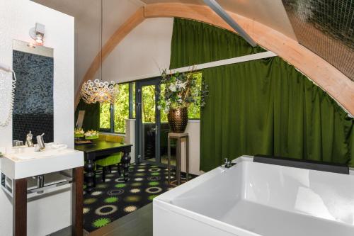 奈凯尔克小红屋酒店的浴室设有白色浴缸和绿色窗帘