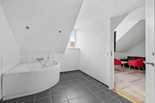 瓦埃勒Best Western ToRVEhallerne的白色的浴室设有浴缸和红色椅子