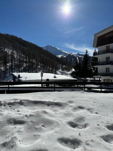 博格塔塞斯特雷Sestriere Borgata appartamento in montagna Casa di Bertu的雪地覆盖的停车场,在雪地里留下脚印