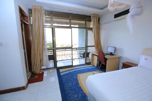 恩德培Frontiers Hotel & Conference Entebbe的配有一张床、一张书桌和一扇窗户的酒店客房