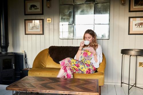 海斯Hog Deer Creek - At Port Lympne Reserve的坐在沙发上喝一杯咖啡的女人