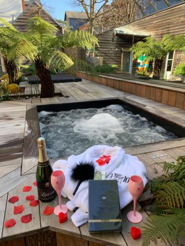 埃特勒塔La villa 10 HÔTEL SPA的热水浴池,提供一瓶香槟和一瓶葡萄酒