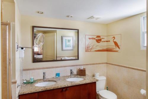 格雷斯湾珊瑚花园格雷斯湾度假村的浴室设有2个水槽、卫生间和镜子。