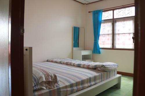 班敦孟ChillHouse24 @ DonMueang的一间卧室配有一张带蓝色窗帘的床和一扇窗户