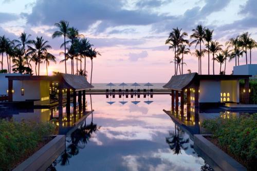 蔻立JW Marriott Khao Lak Resort and Spa的棕榈树和大海的度假村游泳池