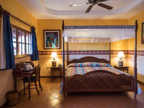格拉纳达Hotel Colonial Granada的一间卧室配有一张天蓬床和一张桌子