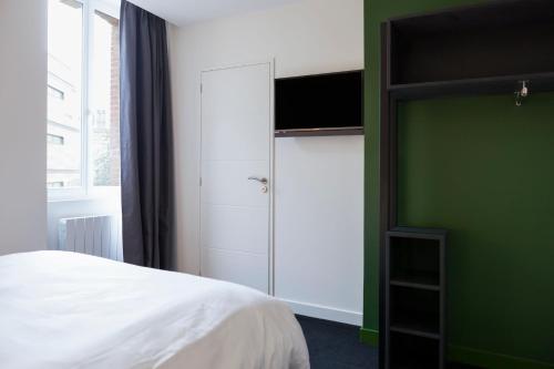 拉瓦勒Logis Hotel du Maine的卧室配有白色的床和绿色的墙壁