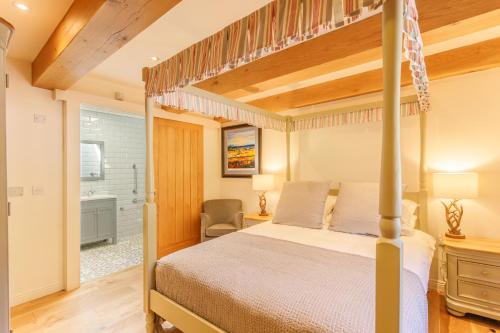 门蒂斯港Gamekeeper's Lodge- a cottage with a spectacular view的一间卧室设有天蓬床和一间浴室。