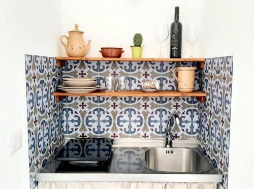 纳尔多Casina Pompiliano的厨房铺有蓝色和白色瓷砖,设有水槽