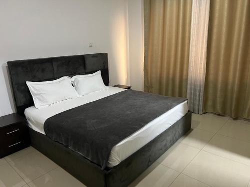 阿克拉Nuben Court-Accra的一间卧室配有一张大床和黑色床头板
