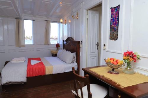 卢克索Dahabiya Giraffa的一间卧室配有一张床和一张桌子及一碗水果