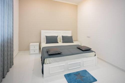 尼甘布Clintonvilla 4-bedroom with pool near to Airport的白色卧室配有一张蓝色地毯的大床