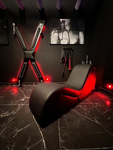 Douchy-les-MinesLoveroom de luxe - Thème 50 nuances de grey maison privative spa insolite的一间黑色和红色的房间,配有红灯和黑椅子