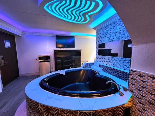 小石城小石城美洲最佳价值套房酒店 的带电视的客房内的大浴缸
