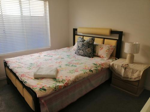 墨尔本Melbourne Lakes warm house的一间卧室配有一张带花卉棉被的床