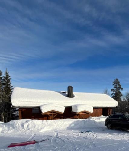 特吕西尔Trysil - Ski in/out的雪上覆盖的小屋,有一辆汽车停放在雪地里