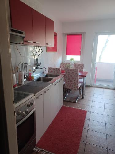 奥西耶克Apartment M&A的厨房配有白色橱柜和红色地毯