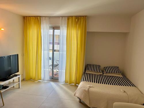 马赛★★★ Paradis Prado Mermoz proximité Mer★★★的一间卧室配有床、电视和黄色窗帘