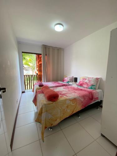 卡马萨里Village Itacimirim的一间卧室配有一张带粉色床单的床和一扇窗户。