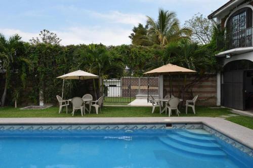 库奥特拉莫雷洛斯Tequesquitengo, Morada del sol的房屋旁的游泳池配有椅子和遮阳伞