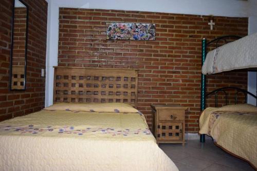 库奥特拉莫雷洛斯Tequesquitengo, Morada del sol的一间卧室设有两张床和砖墙