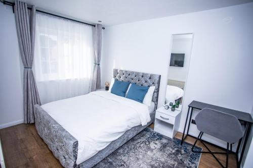 Thamesmeadla vida in casa的一间卧室配有一张带蓝色枕头的床和一张书桌