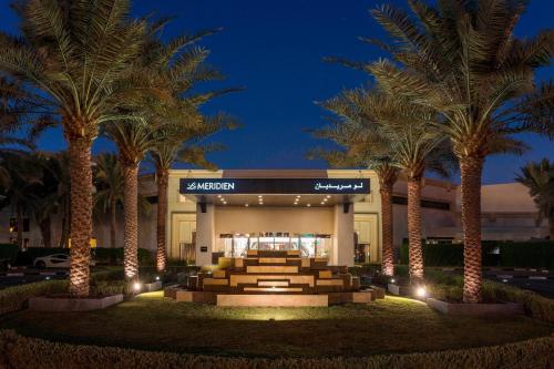 迪拜Le Méridien Dubai Hotel & Conference Centre的一座楼前有棕榈树的酒店