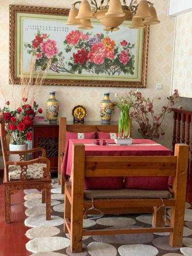 丽江丽江妈妈纳西家庭客栈的一间设有一张桌子和一幅鲜花的用餐室