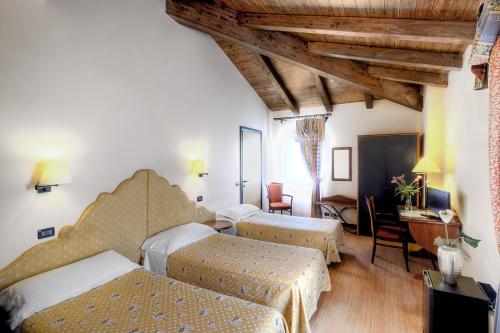 马焦雷堡Antica Locanda Il Sole的酒店客房配有两张床和一张书桌
