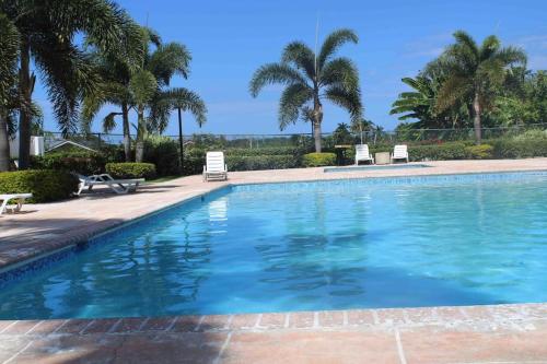 曼米湾Hidden Escape,pool,gated,gym,air-conditioned,的一个带两把椅子的游泳池,棕榈树