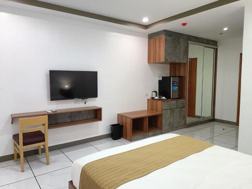 马尼拉Rosh Hotel的卧室配有一张床,墙上配有电视。