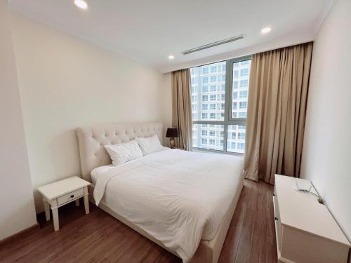 胡志明市Liam Service Apartment - Vinhome Central Park的卧室设有白色的床和大窗户