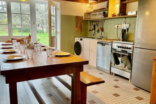 克罗宗Saint Norgard - hameau breton的厨房配有带盘子和玻璃杯的木桌