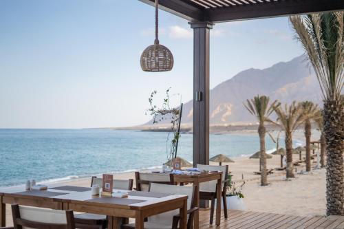 希法西法威精品酒店的海滩上的餐厅,配有桌椅