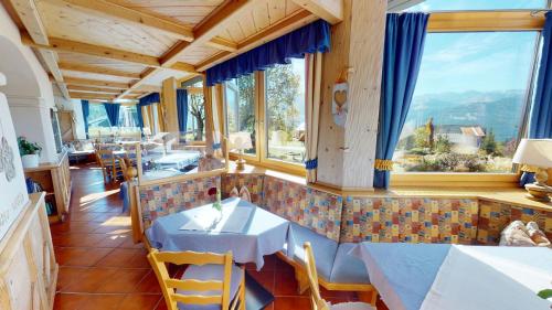 Jenig披若斯劳尔山酒店的餐厅设有桌椅和大窗户。