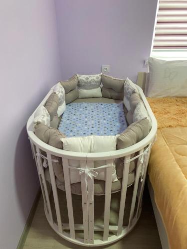 TürkistanApart House的一张白色的婴儿床,在房间内配有一张床