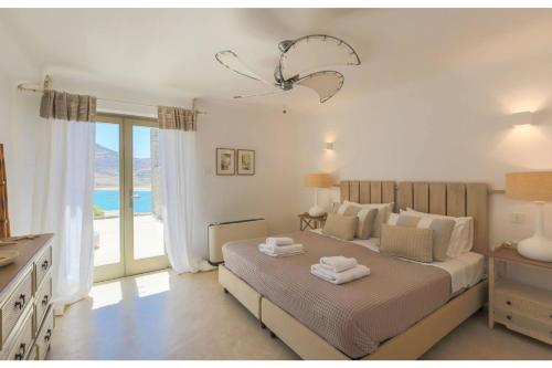 DexamenesElite Mykonos Villa - Villa Roxane - Private Pool - 6 Bedrooms - Beachfront - Ftelia的一间卧室设有一张床和一个大窗户