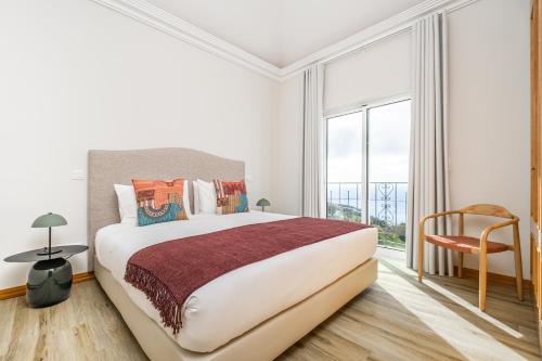 丰沙尔Villa Sea Renity - Palheiro Village by ALMA Holiday Rentals的一间卧室设有一张大床和一个大窗户