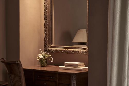 纳夫普利翁波利蒂酒店的镜子和一张桌子,上面有灯和花瓶