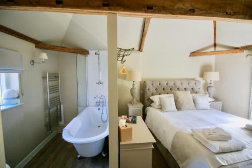 诺里奇Kings Head Bawburgh的一间卧室设有一张大床和一个浴缸