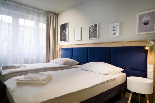 托伦Halo Toruń的卧室内的两张床,配有蓝色床头板
