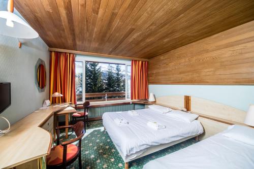 瓦尔Villages Clubs du Soleil - VARS的客房设有两张床、一张桌子和一个窗户。