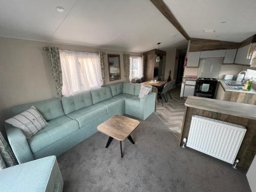 斯凯格内斯Royal Oak Caravan Park的一间带蓝色沙发的客厅和一间厨房