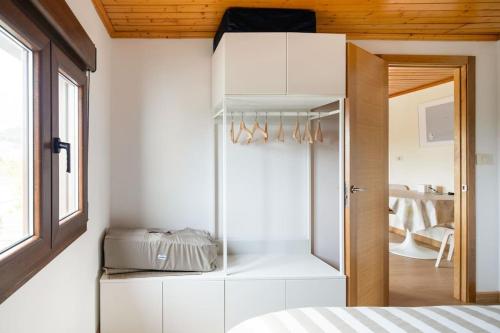 普埃尔托德尔松Ático Porto do Son的卧室设有白色墙壁和玻璃衣柜。